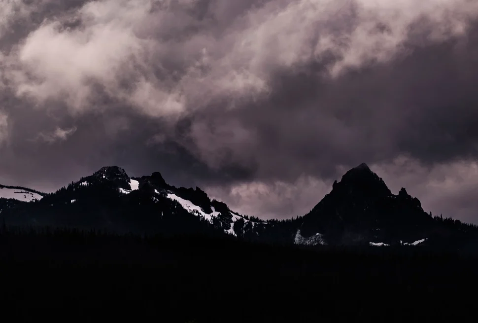 Dark storm clouds gathering over jagged mountain peaks