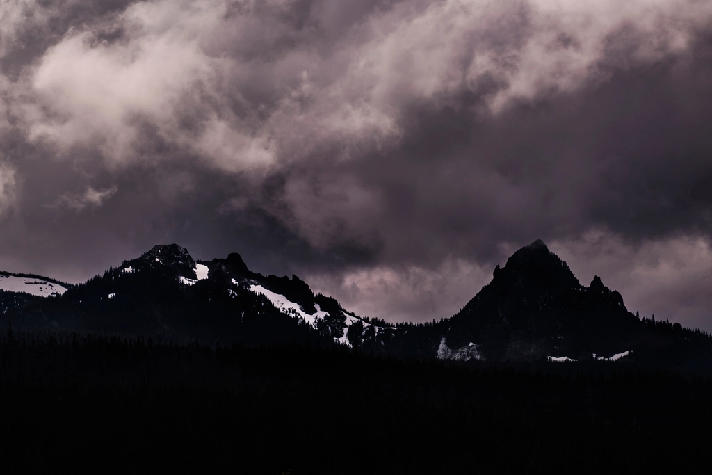 Dark storm clouds gathering over jagged mountain peaks